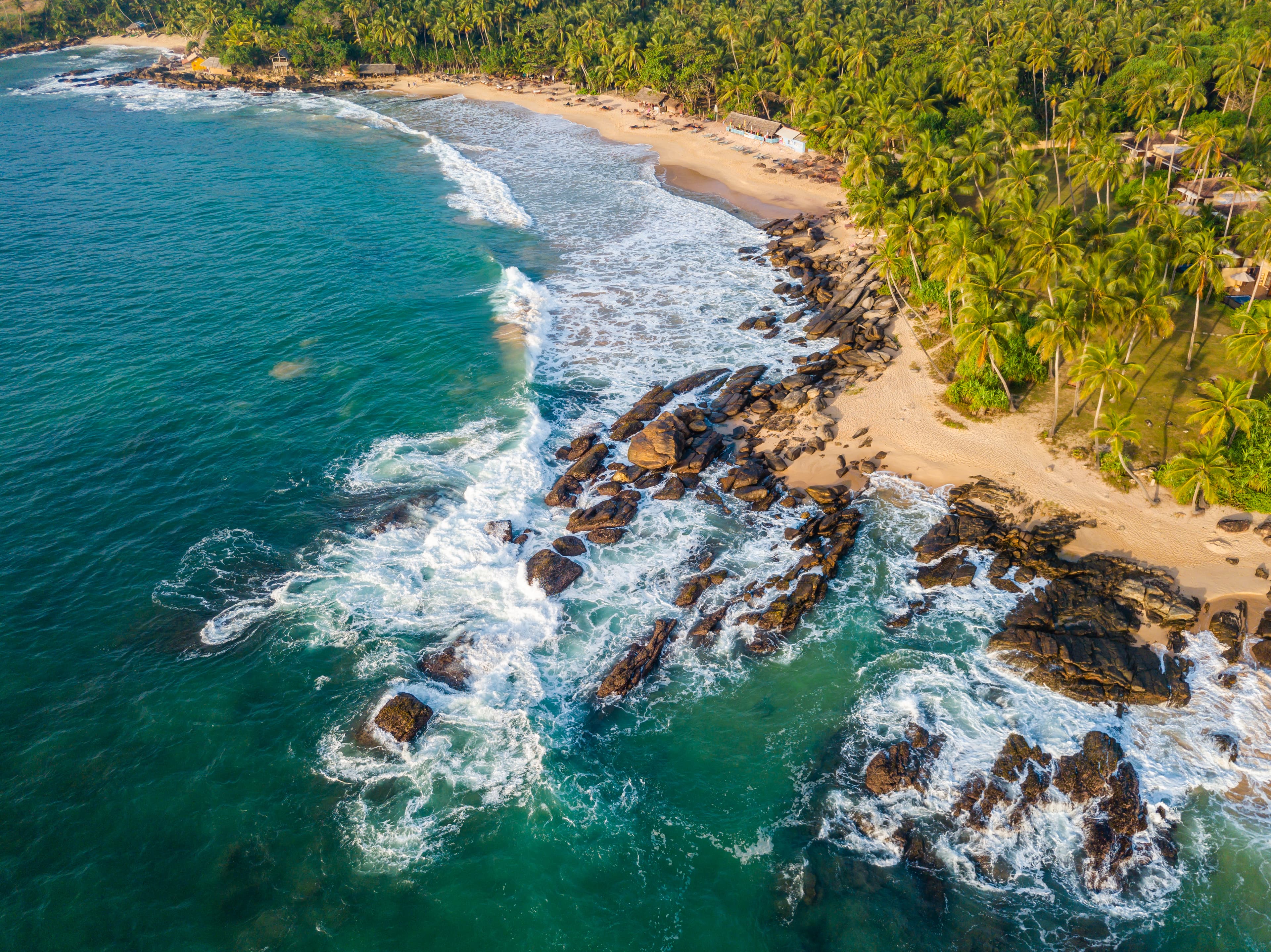 Breathtaking aerial drone view of ocean waves crashing at golden sunset along the Sri Lanka coastline
